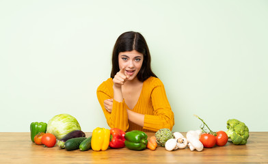 Fototapeta premium Teenager girl with many vegetables surprised and pointing front