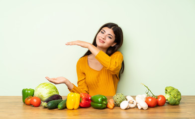 Teenager girl with many vegetables holding copyspace to insert an ad