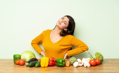 Fototapeta premium Teenager girl with many vegetables suffering from backache for having made an effort