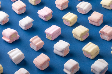 Sweet marshmallows on blue background. Minimalism concept