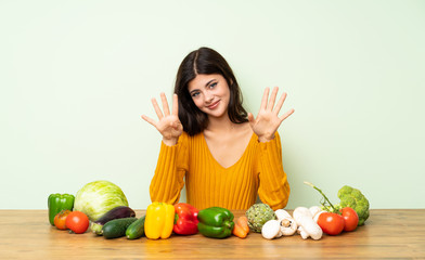 Fototapeta premium Teenager girl with many vegetables counting nine with fingers