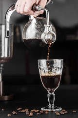 Syphon alternative method of making coffee. coffeemaker is a manual pour-over style glass. Cofee brewing on black background