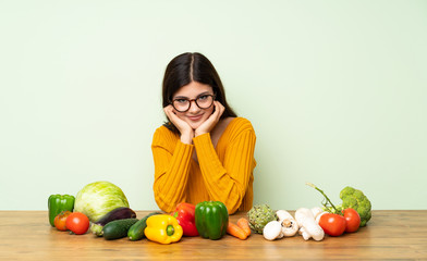 Fototapeta premium Teenager girl with many vegetables with glasses and happy