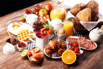 Naklejka na ściany i meble Huge healthy breakfast on table with coffee, orange juice, fruits, waffles and croissants. Good morning concept.