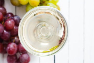 glass of white and red wine and grapes on wooden table