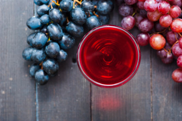 glass of red wine and grapes on black wooden table background