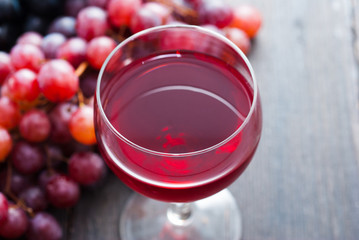 glass of red wine and grapes on black wooden table background