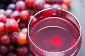 glass of red wine and grapes on black wooden table background