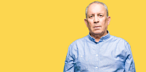 Handsome senior businesss man wearing elegant shirt with serious expression on face. Simple and...