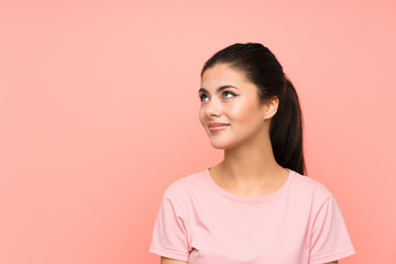 Teenager girl over isolated pink background laughing and looking up