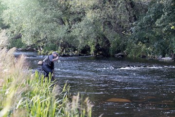 fisherman standing in the river and fly fishing