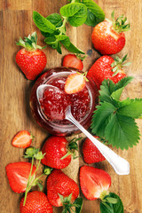 strawberry jam with fresh strawberries and mint. marmalade on spoon and jar on brown wood