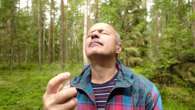 Mature man using mosquito or insect repellent spray