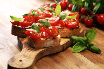 Traditional italian antipasto bruschetta appetizer with cherry tomatoes, cream cheese, basil leaves and balsamic vinegar on cutting board. Antipasti - obrazy, fototapety, plakaty