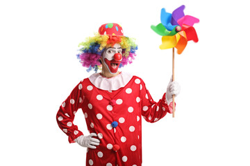 Cheerful clown holding a colorful pinwheel and looking at the camera