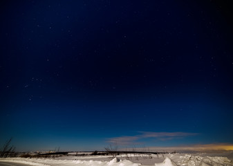 Dark blue sky and stars above the snowy plain.