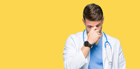 Handsome doctor man wearing medical uniform over isolated background tired rubbing nose and eyes...