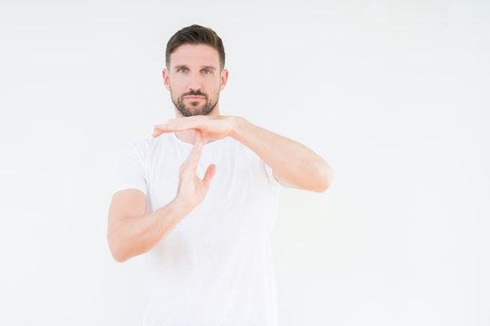 Young handsome man wearing casual white t-shirt over isolated background Doing time out gesture with hands, frustrated and serious face