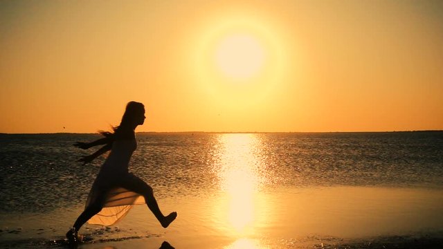 Beautiful girl jumping on the lake coast at sunset, Genichesk, U