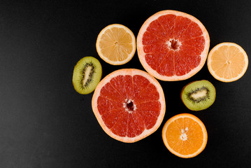 Mix of orange, kiwi, grapefruit on black background. Citrus fruit. Healthy freshness food. Orange fruit with vitamin