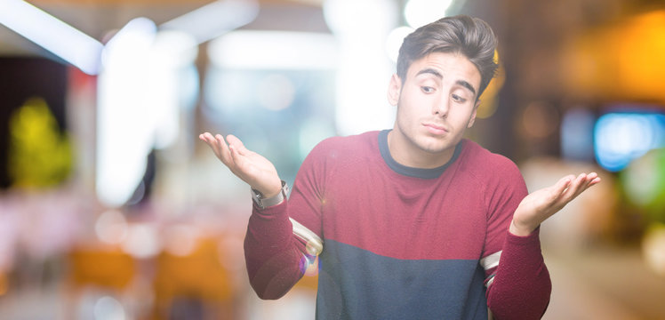 Young handsome man over isolated background clueless and confused expression with arms and hands raised. Doubt concept.