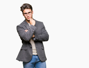 Young business man wearing glasses over isolated background with hand on chin thinking about question, pensive expression. Smiling with thoughtful face. Doubt concept.