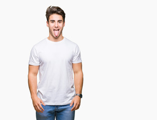 Obraz premium Young handsome man wearing white t-shirt over isolated background sticking tongue out happy with funny expression. Emotion concept.