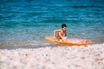 Boy playing in the sea with air mattress
