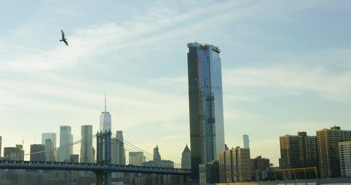 Slow Motion Shot of Manhattan Bridge  Travelling On Hudson River In The Sun With Beautiful New York Skyline And Impressive Skyscrapers