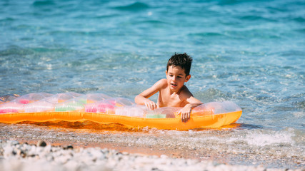 Boy playing in the sea with air mattress