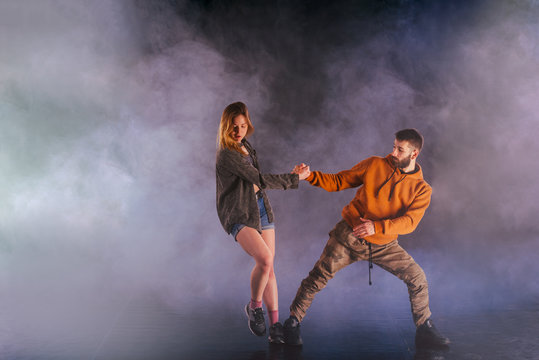 Young couple dancing on the dark background © qunica.com