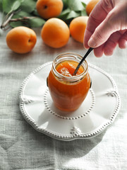 Homemade apricot jam in jar and fresh apricots on background.