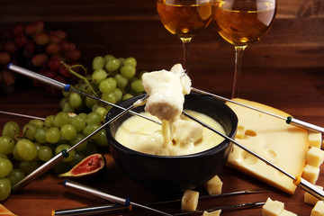 Gourmet Swiss fondue dinner on a winter evening with assorted cheeses on a board alongside a heated...