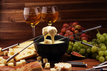 Gourmet Swiss fondue dinner on a winter evening with assorted cheeses on a board alongside a heated pot of cheese fondue