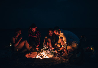 Friends were sitting around the fire while drinking beer and playing guitar
