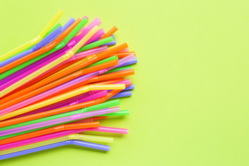 Colorful plastic  straws on green background.