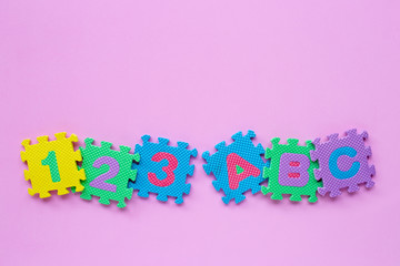 Alphabet puzzle with number puzzle on pink background.