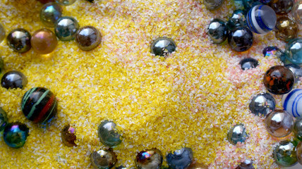 bright background beautiful colorful glass balls in yellow with pink and white sand