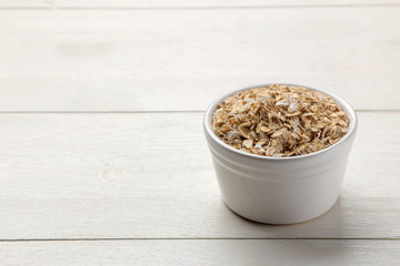 Dry oatmeal flakes in a bowl on a white wooden table. healthy nutrition. healthy food.
