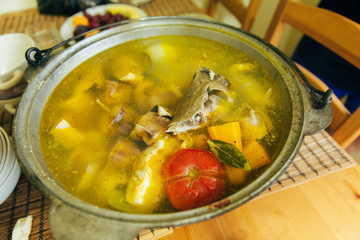 Fish soup boils in a cauldron, picnic in nature