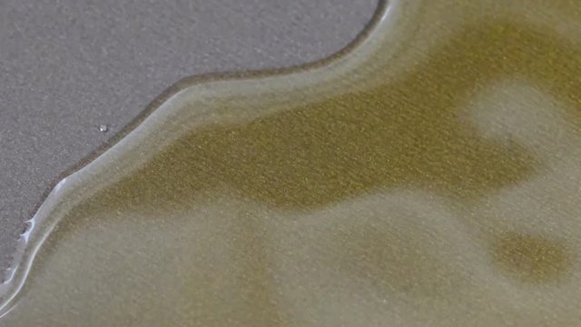 Olive oil is poured in a thin stream on a non-stick, coated teflon pan, video clip close-up video using zoom and camera movement