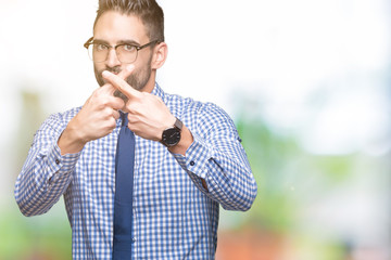 Young business man wearing glasses over isolated background Rejection expression crossing fingers doing negative sign