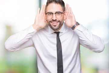 Young handsome business man wearing glasses over isolated background Trying to hear both hands on ear gesture, curious for gossip. Hearing problem, deaf