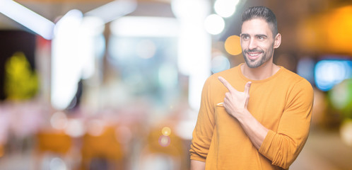Fototapeta na wymiar Young handsome man over isolated background cheerful with a smile of face pointing with hand and finger up to the side with happy and natural expression on face