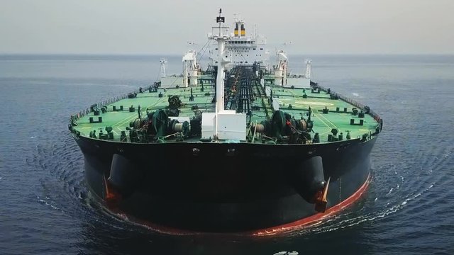 Bow and front deck of a tanker ship underway in the ocean. Aerial frontal view as crude oil tanker ploughs through waters at sea. Full loaded vessel moves at calm waters. Close up of bulbous bow break