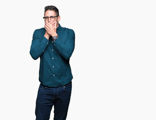 Young handsome business man wearing glasses over isolated background shocked covering mouth with hands for mistake. Secret concept.