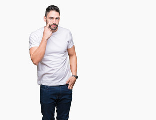 Fototapeta premium Handsome man wearing white t-shirt over white isolated background Pointing to the eye watching you gesture, suspicious expression