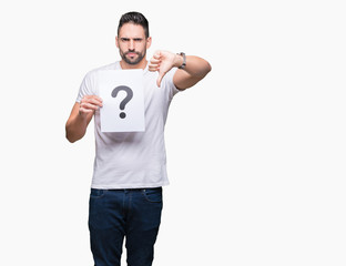 Handsome young man holding paper with question mark over isolated background with angry face,...