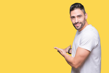 Handsome man wearing white t-shirt over yellow isolated background Inviting to enter smiling natural with open hand