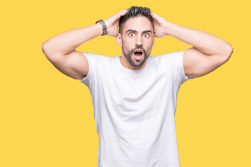 Fototapeta na wymiar Handsome man wearing white t-shirt over yellow isolated background Crazy and scared with hands on head, afraid and surprised of shock with open mouth
